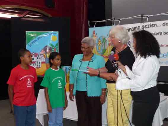 Marie Wijk en enkele Surinaamse kinderen bieden 'First Lady' Liesbeth Venetiaan eerste boek aan